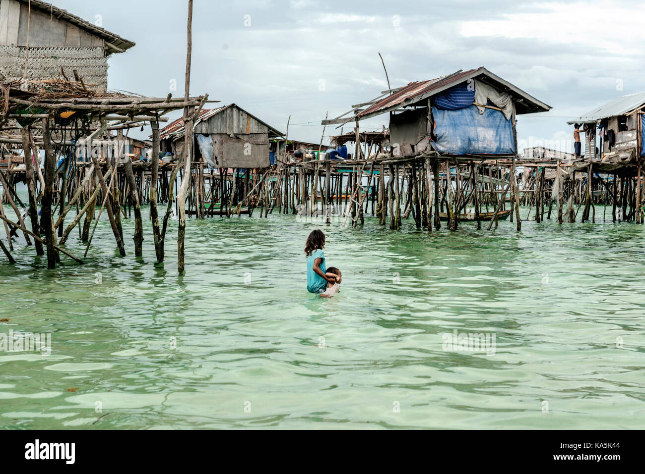 Bambina che porta il suo fratello a casa in Semporna villaggio sul mare, Malaysia Foto Stock
