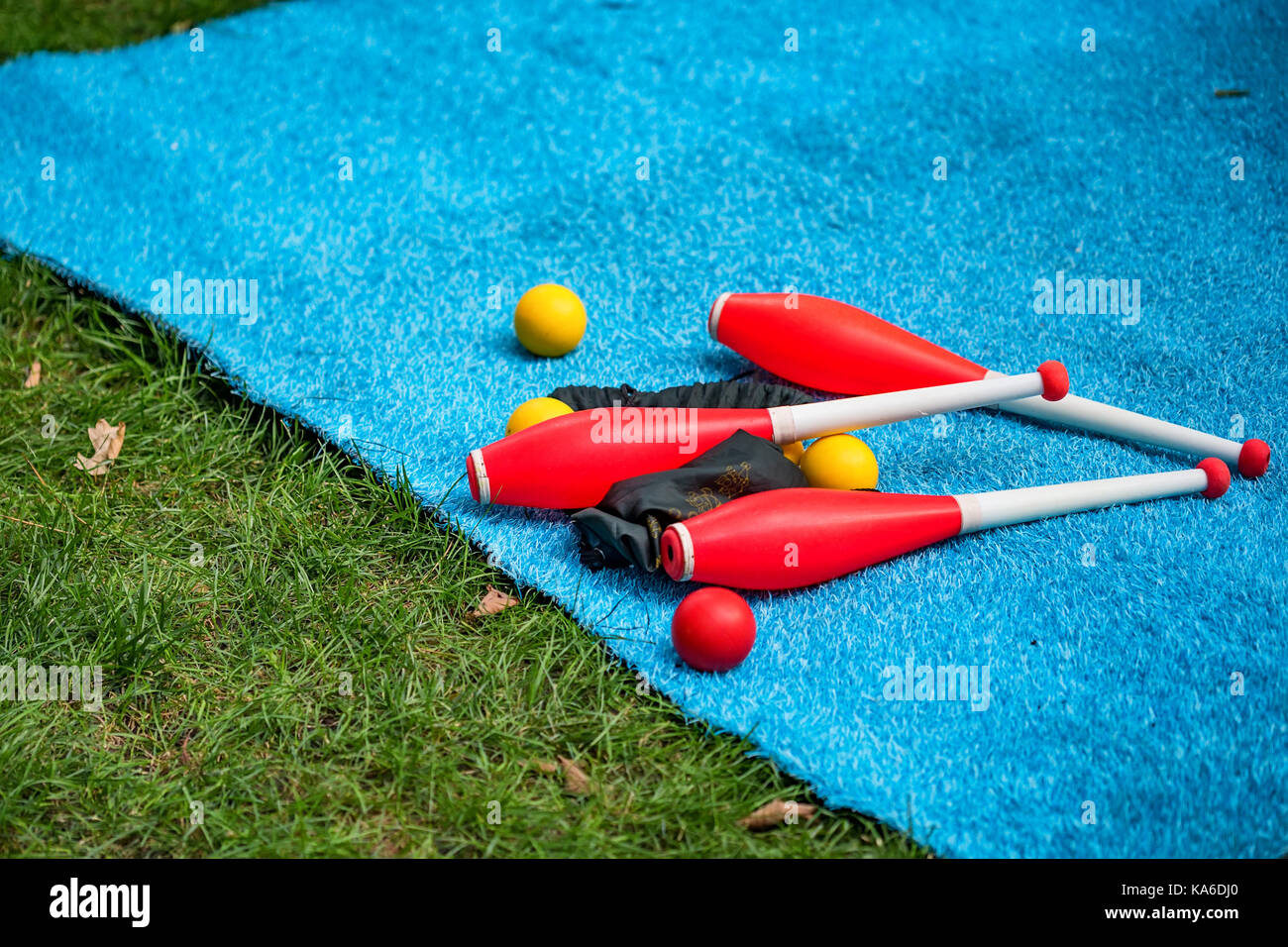 Club di giocoleria e sfere giacciono sul tappeto blu di close-up Foto Stock