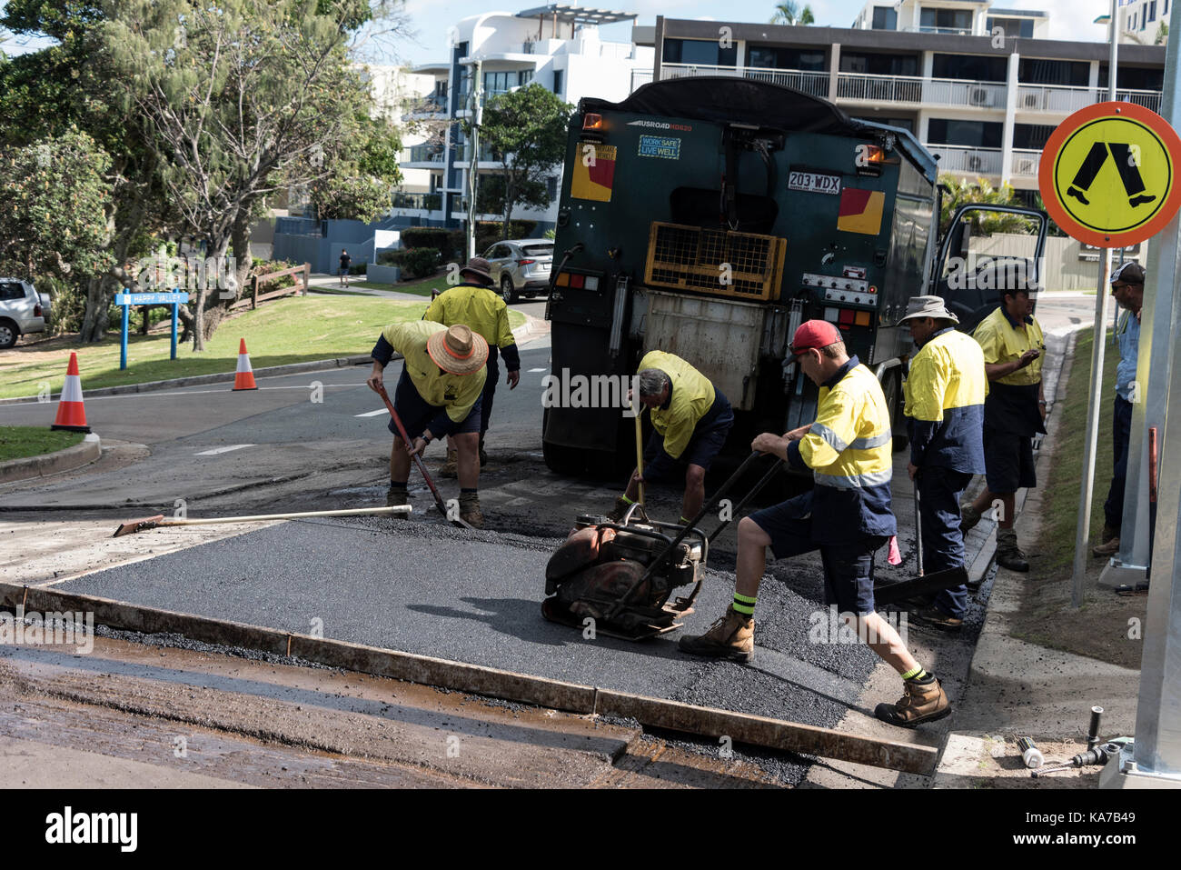 Una manutenzione stradale equipaggio ri-affiorare una strada in caloundra, Queensland, Australia Foto Stock