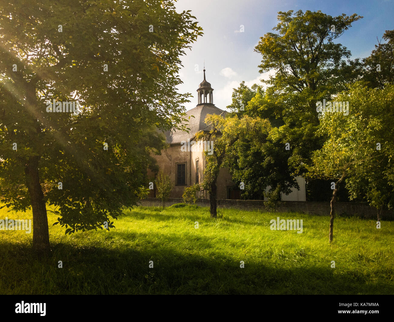 Una chiesa abbandonata nascosto dietro gli alberi in una giornata di sole in autunno Foto Stock