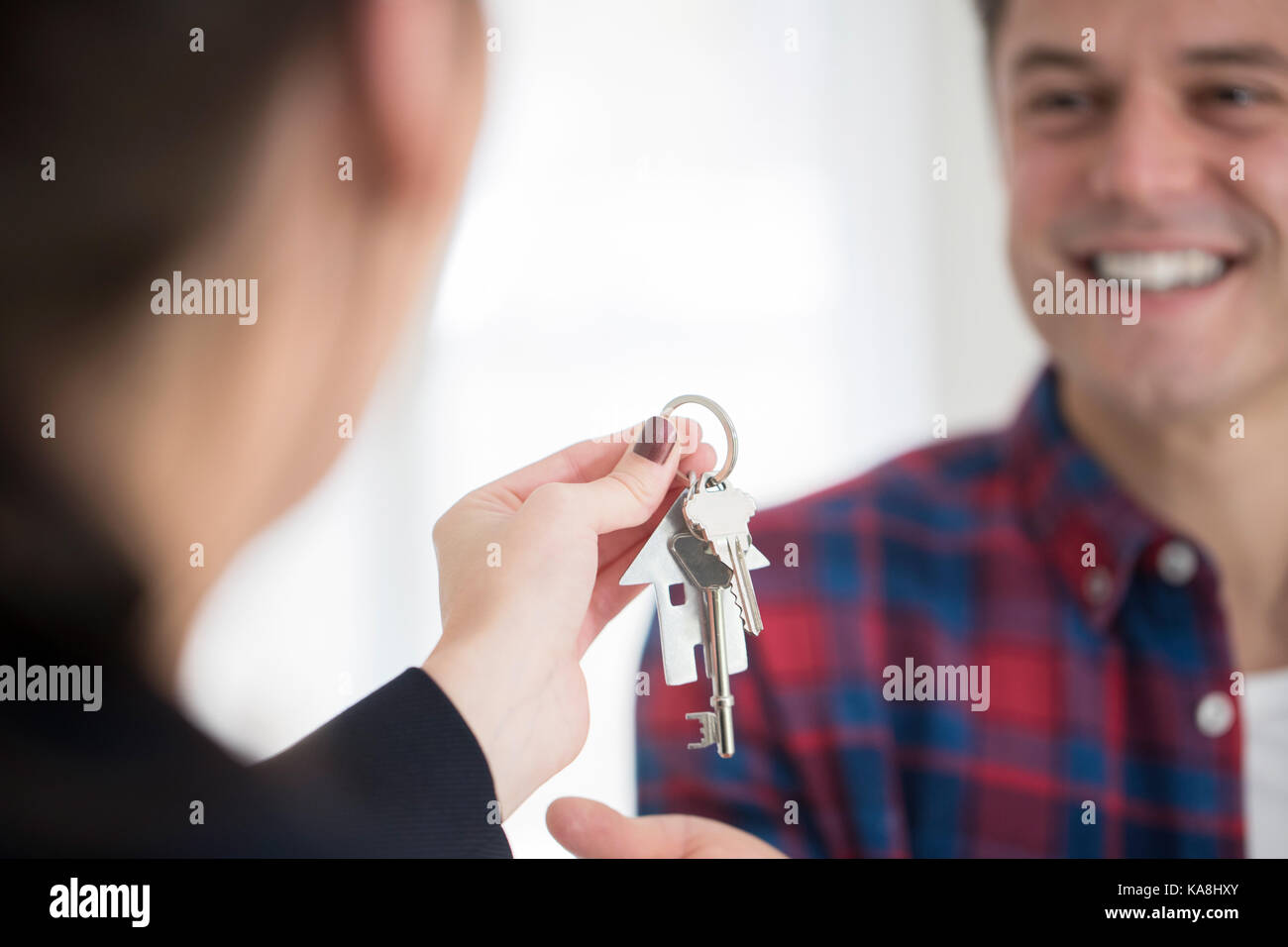 L'uomo raccogliendo le chiavi di casa nuova da agente immobiliare femmina Foto Stock