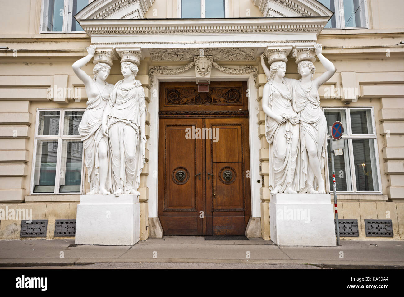 Cariatidi presso il portale del palazzo neoclassico Palazzo Pallavicini a Vienna, Austria. Un riccamente decorata porta in legno che costituisce l'ingresso. Foto Stock