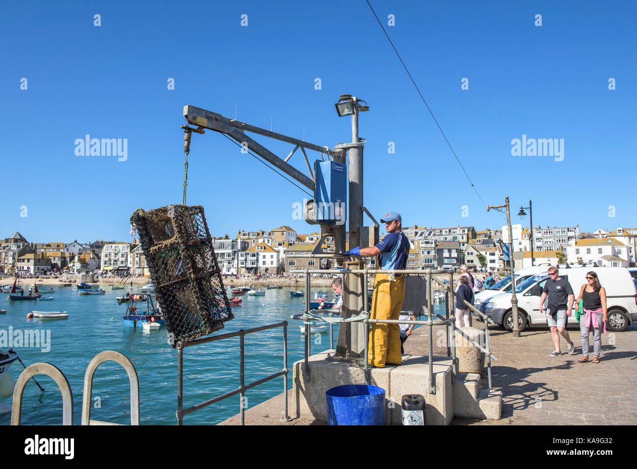 St Ives industria della pesca - un pescatore utilizzando un paranco per scaricare il granchio aragosta pentole su Smeatons Molo di St Ives in Cornovaglia. Foto Stock