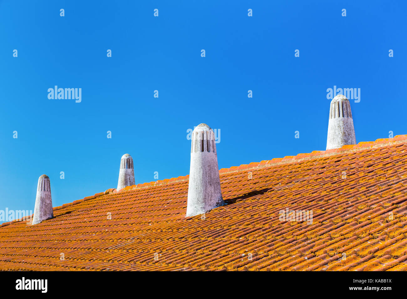 Orange tegole del tetto con quattro camini di bianco e blu cielo Foto Stock