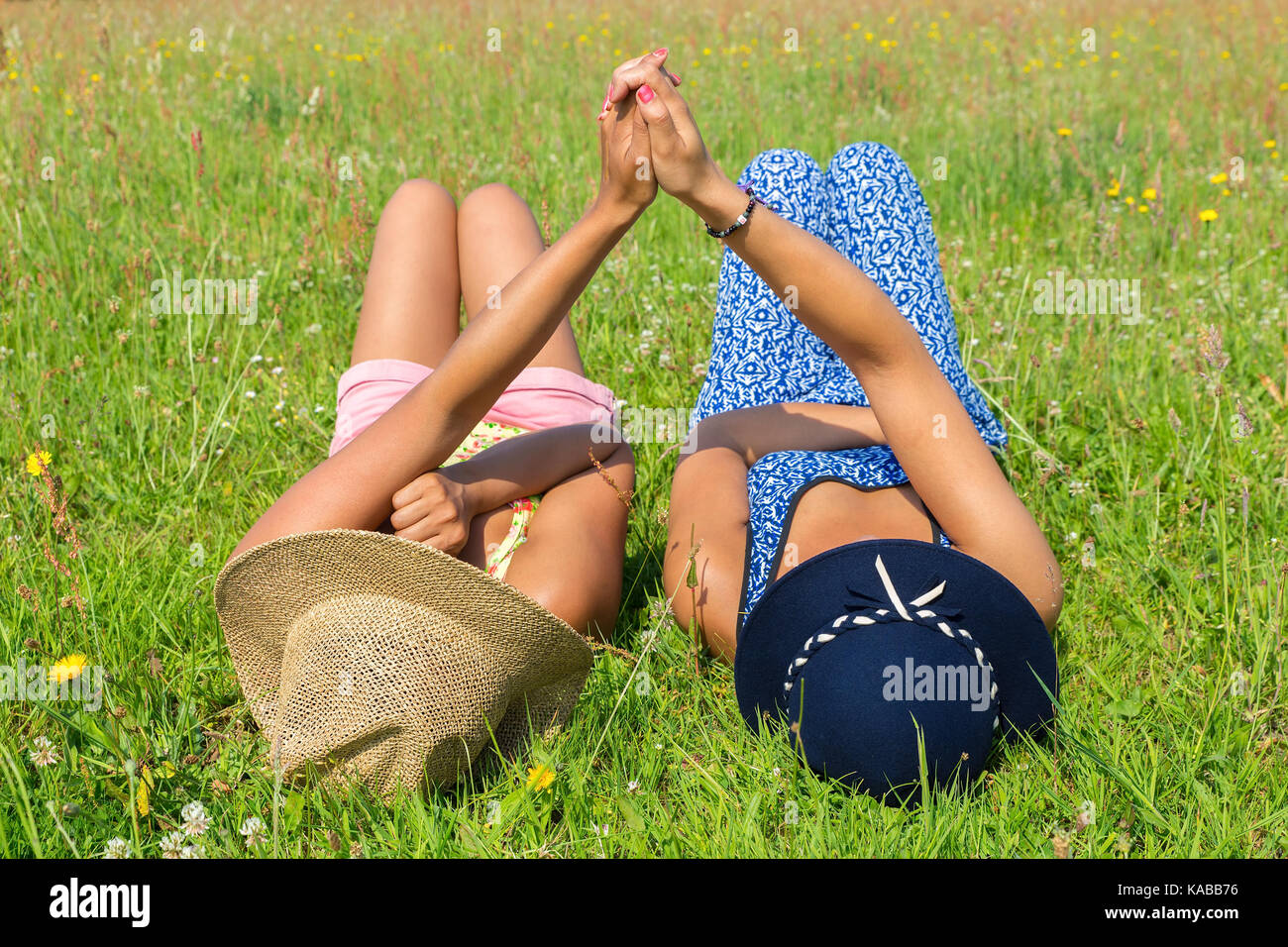 Due giovani donne giacente insieme in erba verde Foto Stock