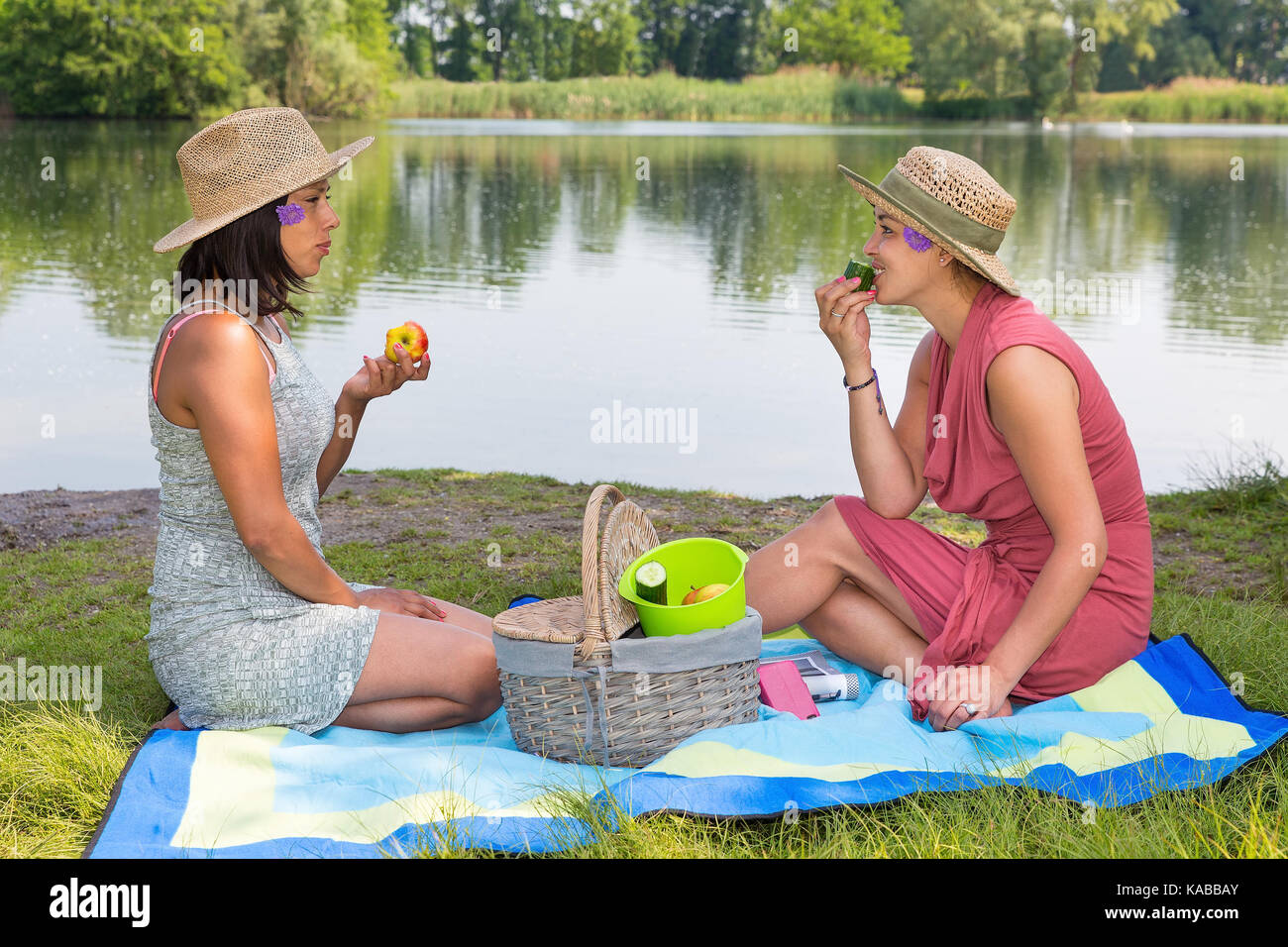 Due amici picknicking a lato acqua Foto Stock
