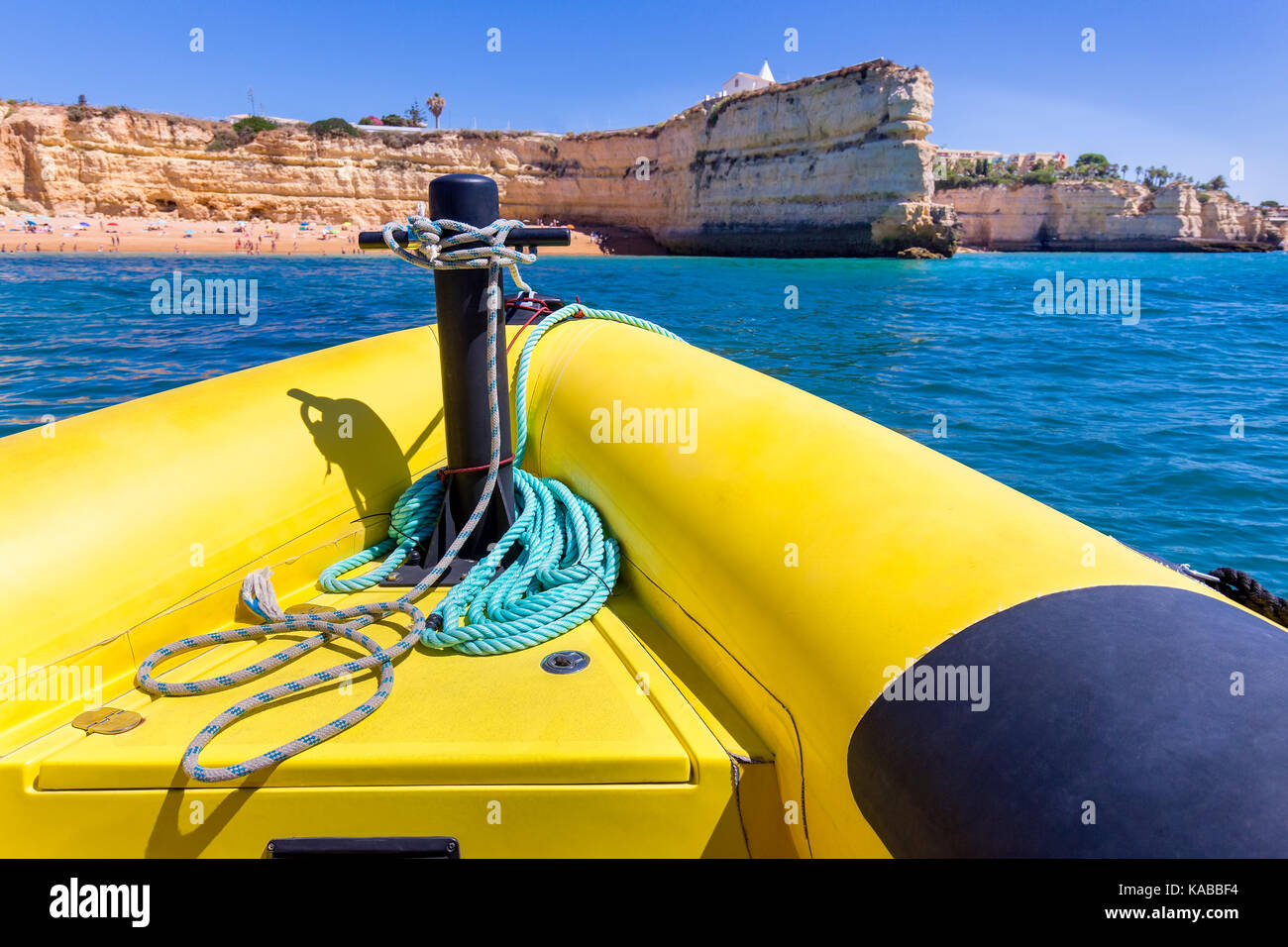 Gomma gialla in barca a vela verso le rocce in costa Foto Stock