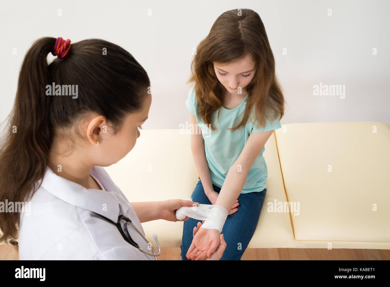 Medico donna del bendaggio mani delle bambine in clinica Foto Stock