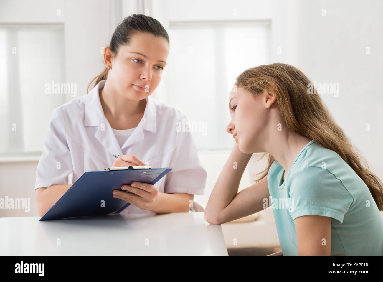 Medico donna consolante paziente depresso seduta a tavola Foto Stock