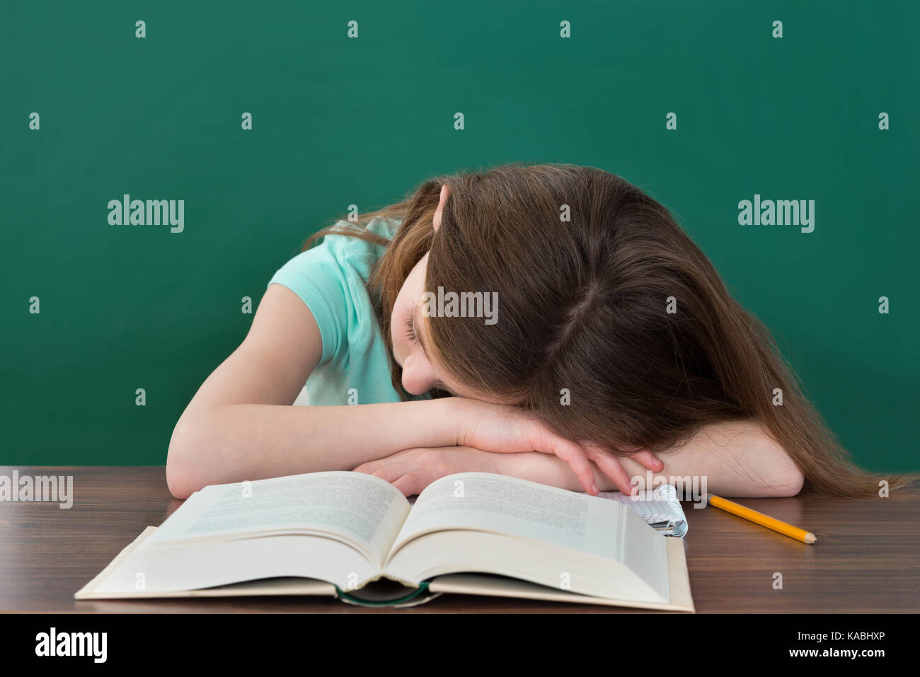 Stanco studente con libri e matita a dormire la scrivania in aula Foto Stock