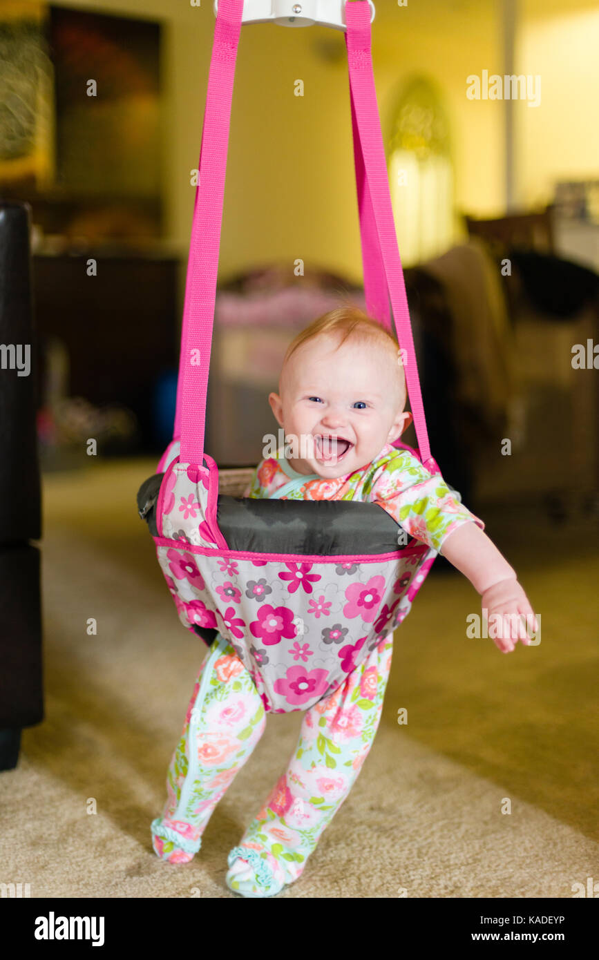 Sei mesi Baby girl in baby bouncer Ridere e divertirsi Foto Stock