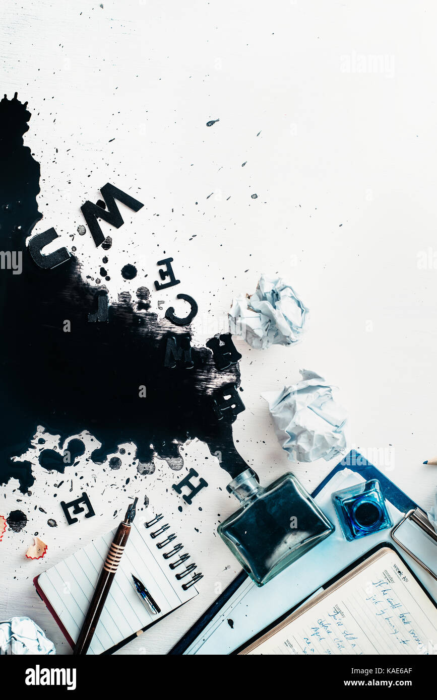 Scrittore workplace con eventuali fuoriuscite di inchiostro, carta sgualcita, sparsi in lettere, carte e taccuini su un bianco sullo sfondo di legno. testata con la scrittura creativa c Foto Stock