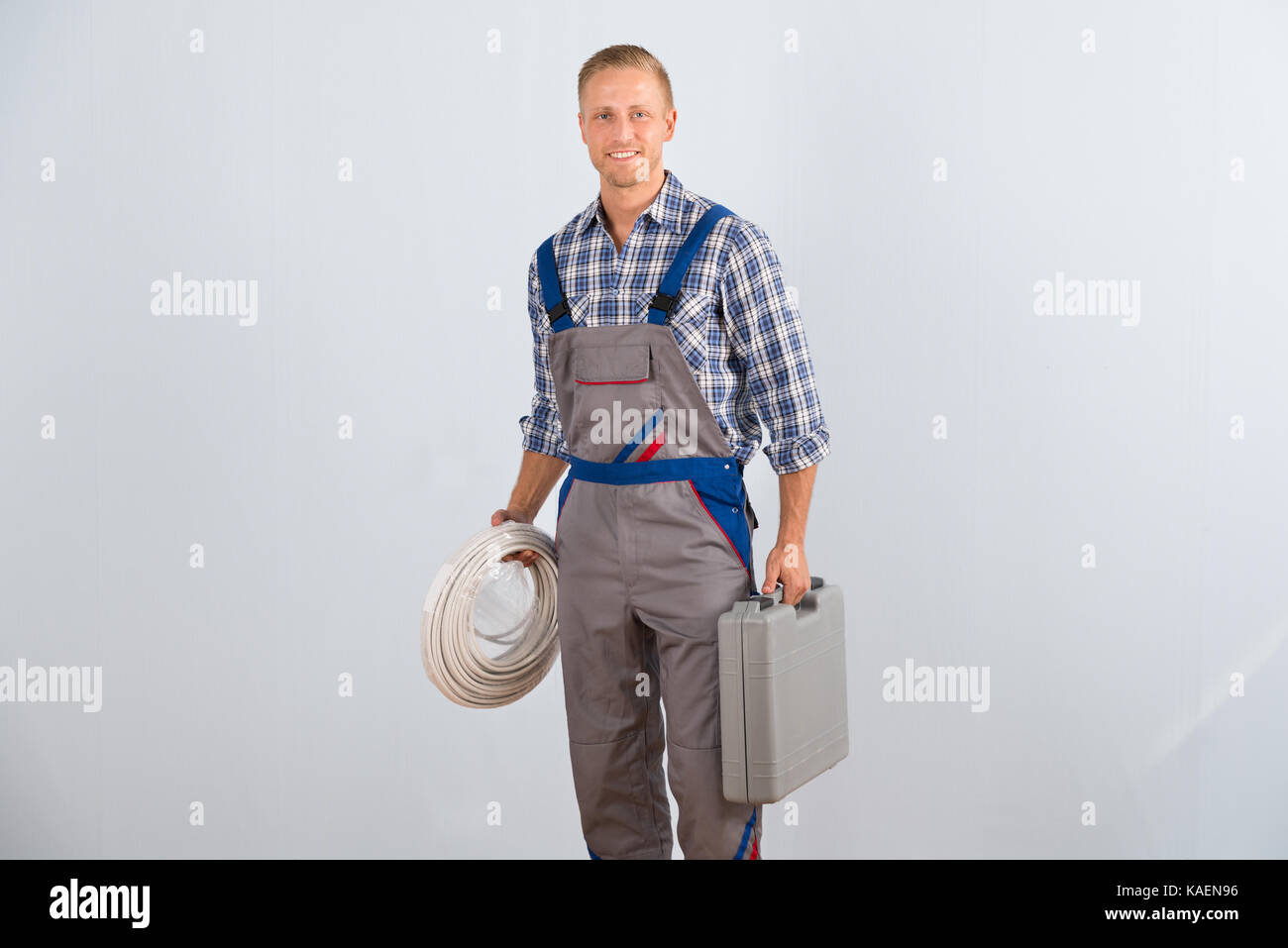 Giovani felici elettricista cavi di contenimento e la casella degli strumenti Foto Stock