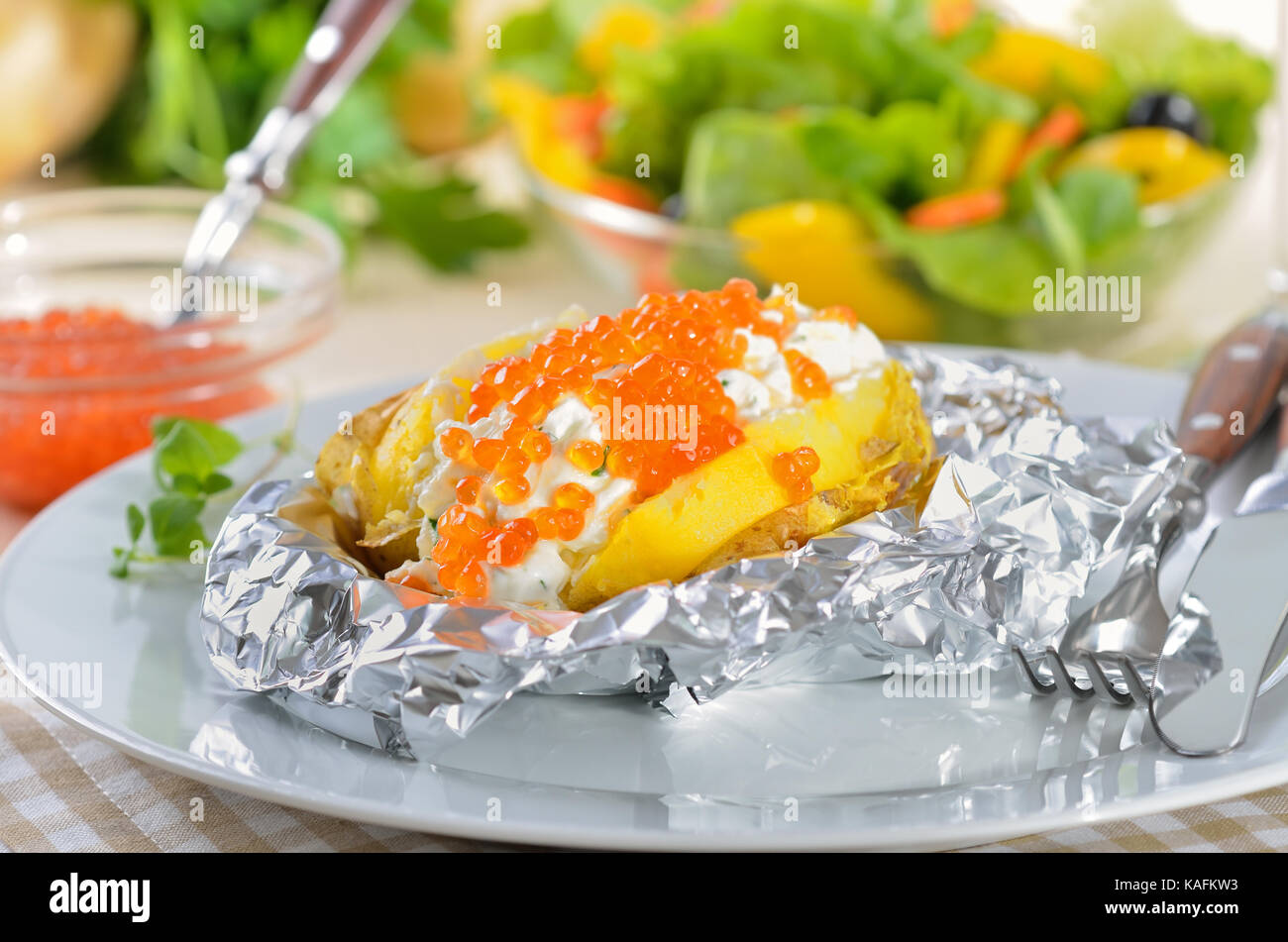 Giacca cotti al forno con patate condito di crema di formaggio e russo caviale di trota, guarnita con maggiorana Foto Stock