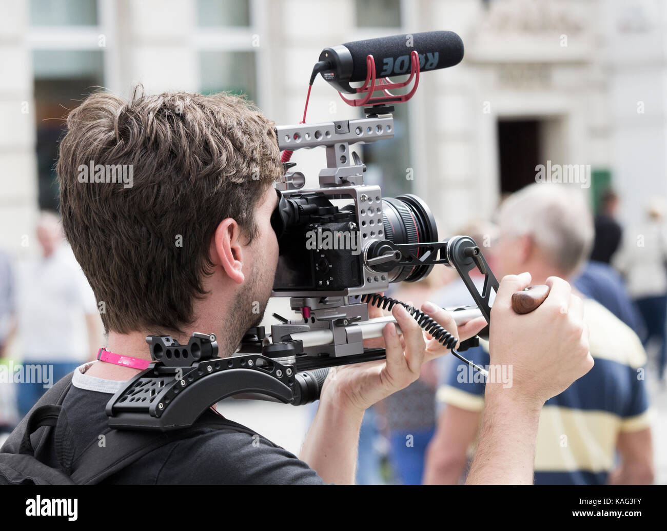 Uomo che realizza video con la fotocamera DSLR supportata sul supporto per le spalle Foto Stock