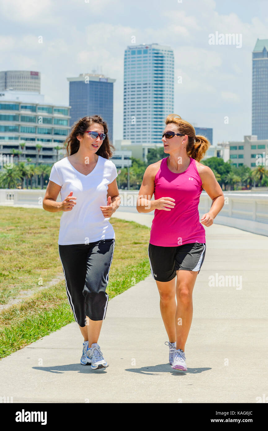 Due donne a fare jogging lungo il Bayshore Boulevard con il centro di Tampa, Florida, Stati Uniti d'America skyline in background. Foto Stock