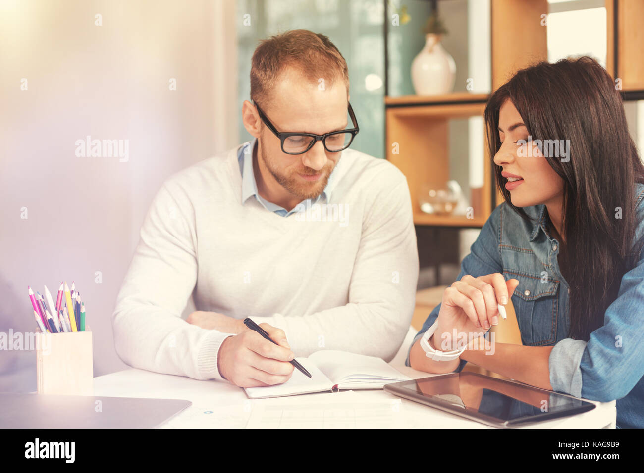 Guarda questa. focalizzato giovani colleghi seduti ad un tavolo mentre si discute di un serio progetto e lavorare come un team aziendale. Foto Stock