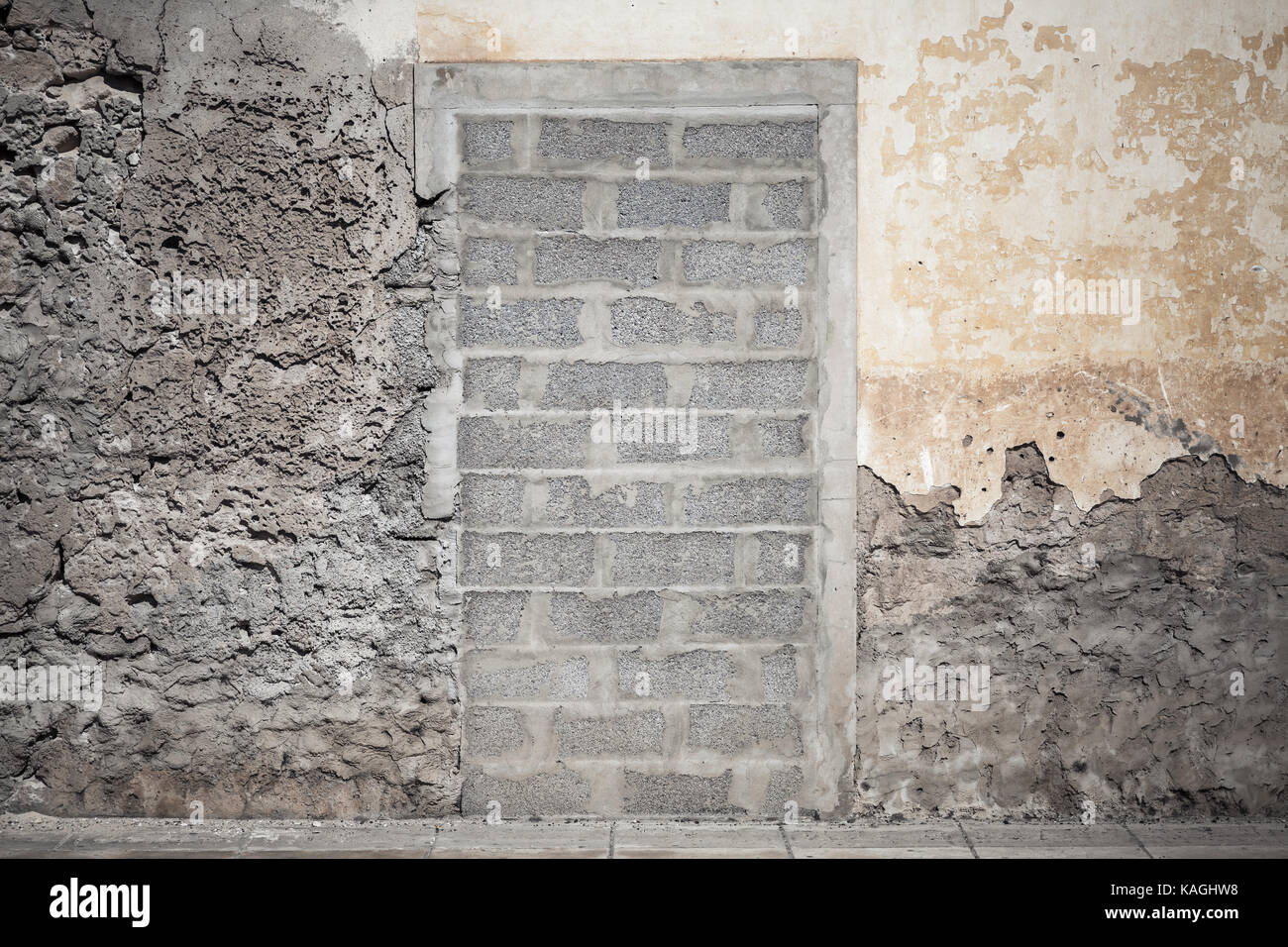 Porta nel vecchio muro giallo bloccato con mattoni di calcestruzzo. foto di sfondo texture Foto Stock