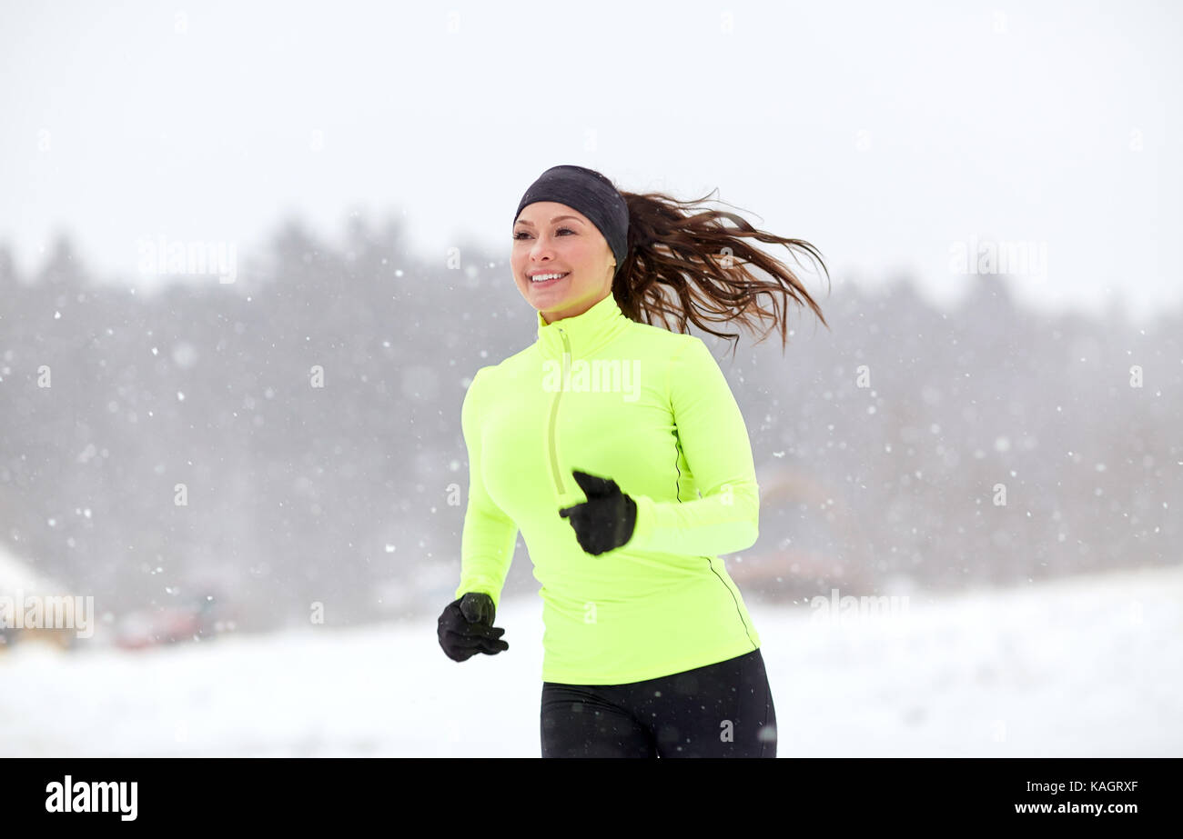 Donna felice che corre lungo strade coperte di neve in inverno road Foto Stock