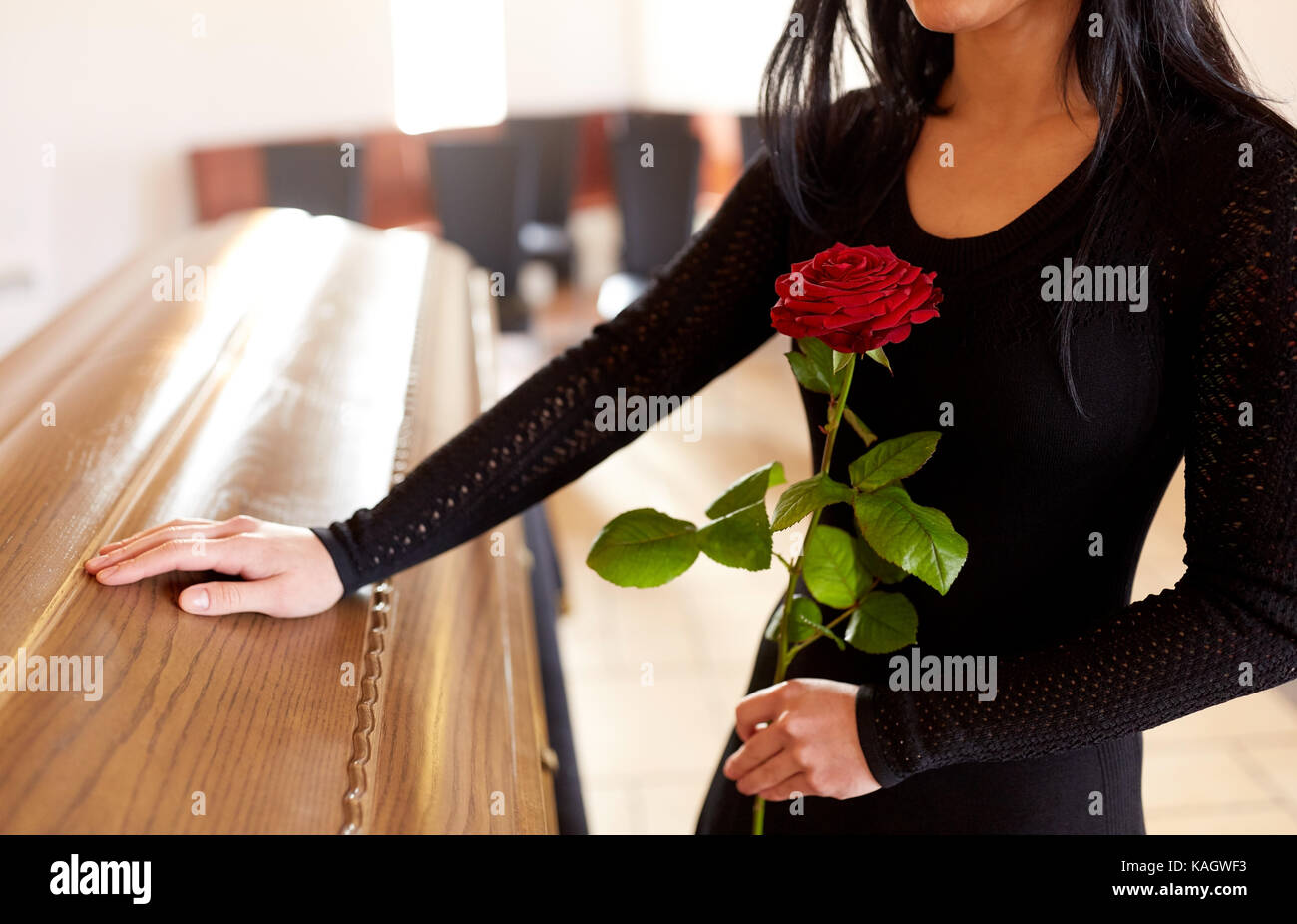 Donna con rose rosse e bara al funerale Foto Stock