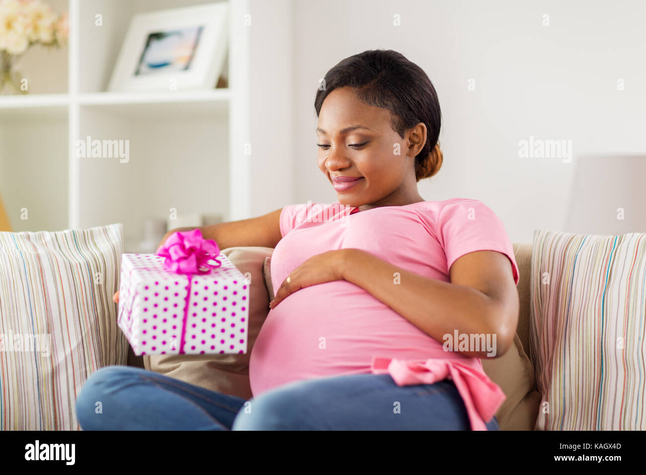 Felice americano africano donna incinta con il dono Foto Stock