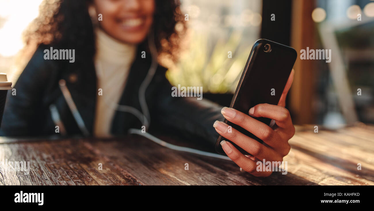 Donna della chat video sul telefono cellulare in una caffetteria. Immagine ravvicinata di uno smartphone utilizzato da una donna seduta al tavolo. Foto Stock