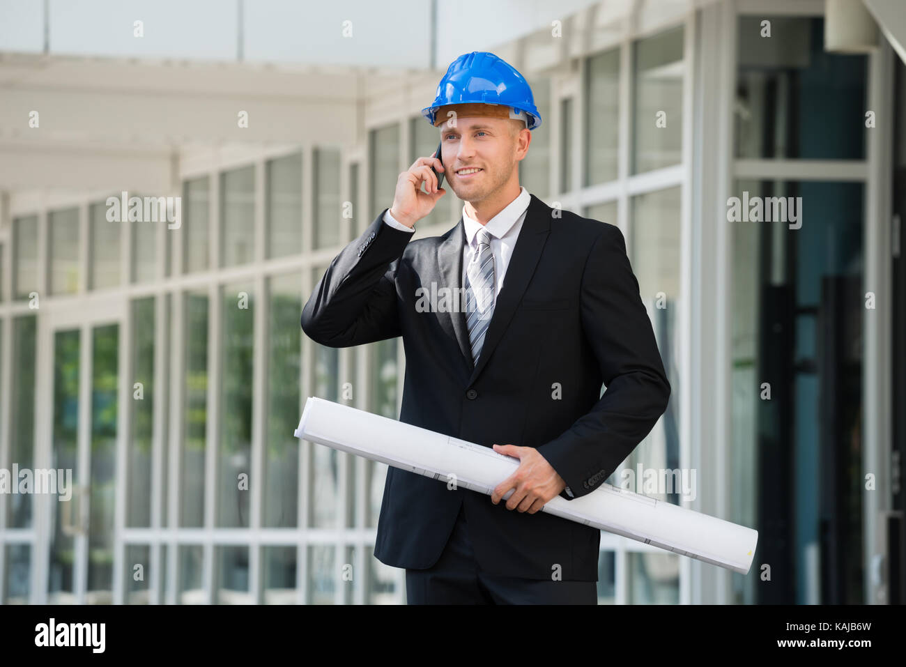 Giovane ingegnere Azienda Blue Stampa parlando al cellulare Foto Stock