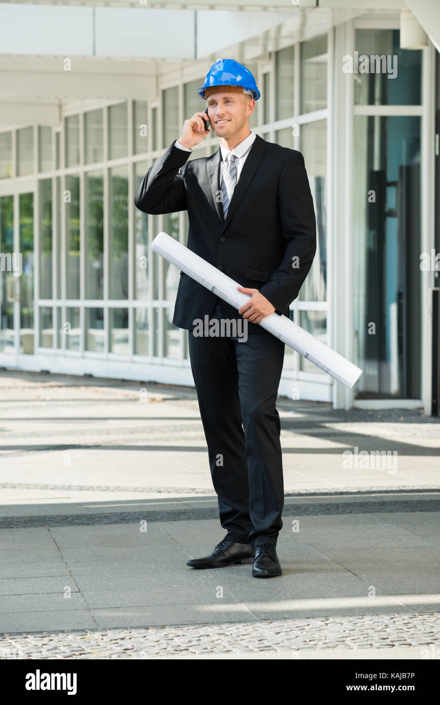 Giovane ingegnere Azienda Blue Stampa parlando al cellulare Foto Stock