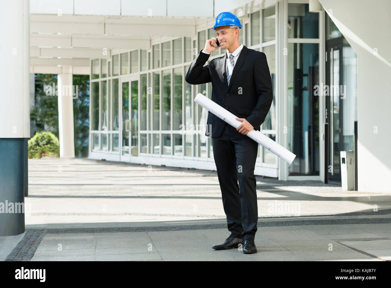 Giovane ingegnere Azienda Blue Stampa parlando al cellulare Foto Stock