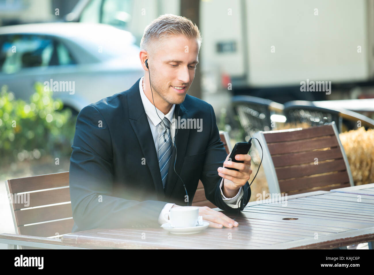 Imprenditore seduta sul banco di lavoro ascoltando la musica sul telefono cellulare Foto Stock