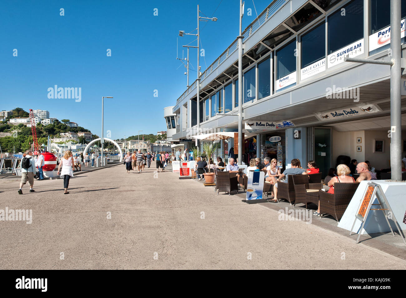 Turisti che si godono una sala da pranzo alfresco presso la marina al beacon quay torquay devon con vista del punto di fuga di una scultura in background Foto Stock