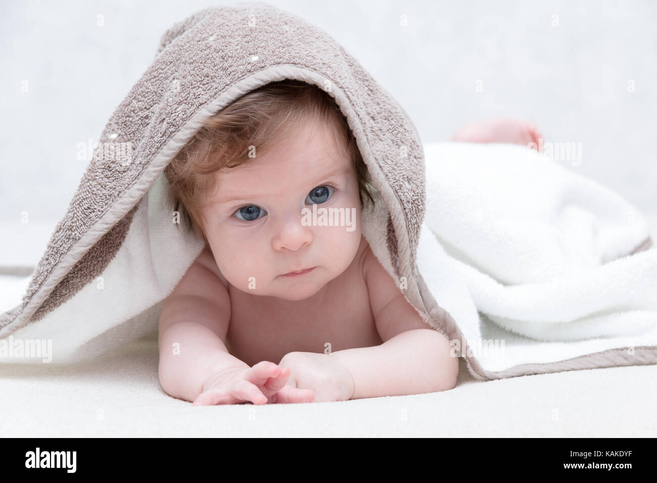 Carino neonato ragazza con bellissimi occhi azzurri su una spugna bianca  coverlet. adorabile baby guardando fuori sotto una coltre bianca o  asciugamano. triste bambina in asciugamano bianco dopo la doccia Foto stock  -
