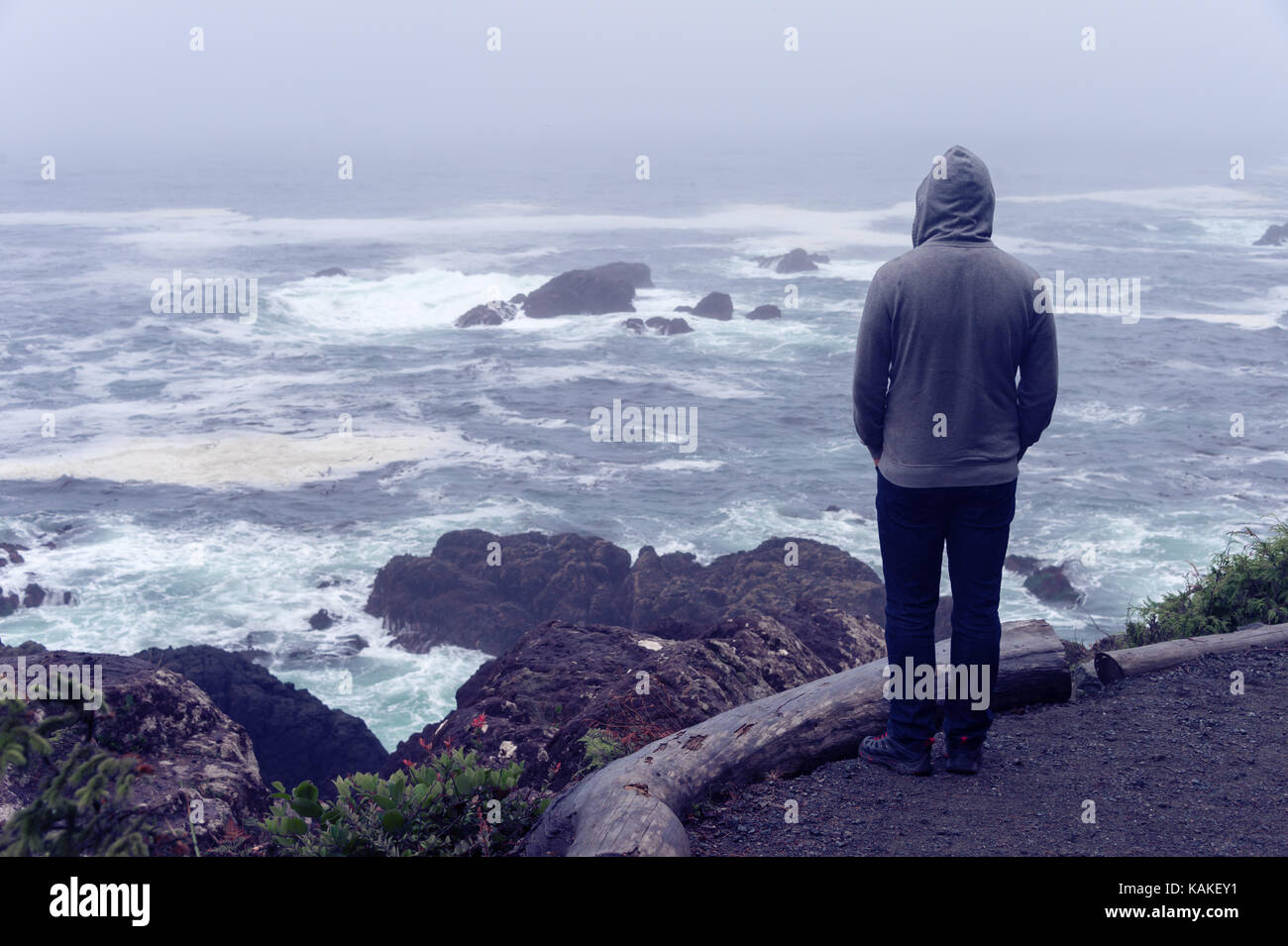 Lonely Man standing di fronte all'oceano pacifico e guardando il mare tempestoso sull'isola di Vancouver. Foto Stock
