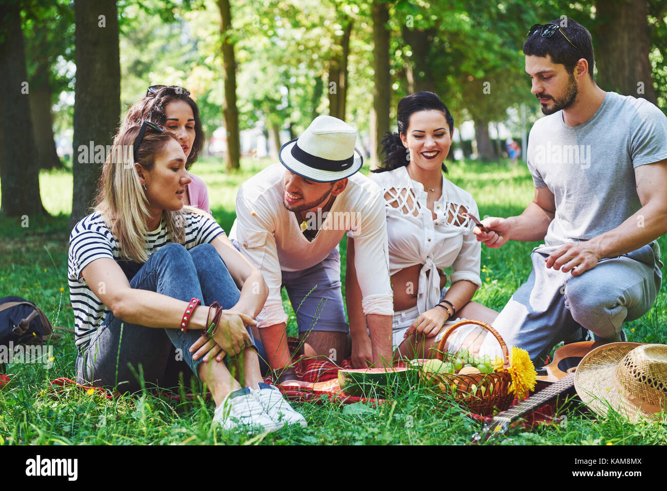 Gruppo di amici avente pic-nic in un parco in una giornata di sole - persone appendere fuori, per divertirsi durante la cottura e rilassante Foto Stock