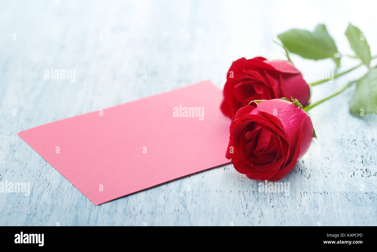 Le rose e il bigliettino vuoto su un tavolo di legno Foto Stock