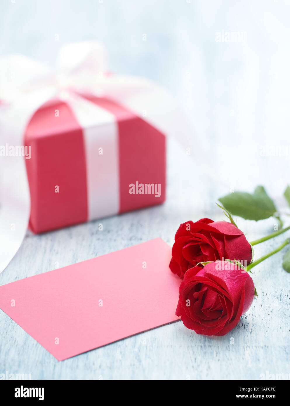 Le rose e il bigliettino vuoto su un tavolo di legno Foto Stock