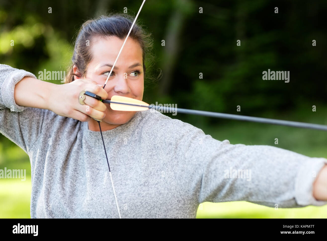 Atleta fiducioso puntando con arco e frecce nella foresta Foto Stock