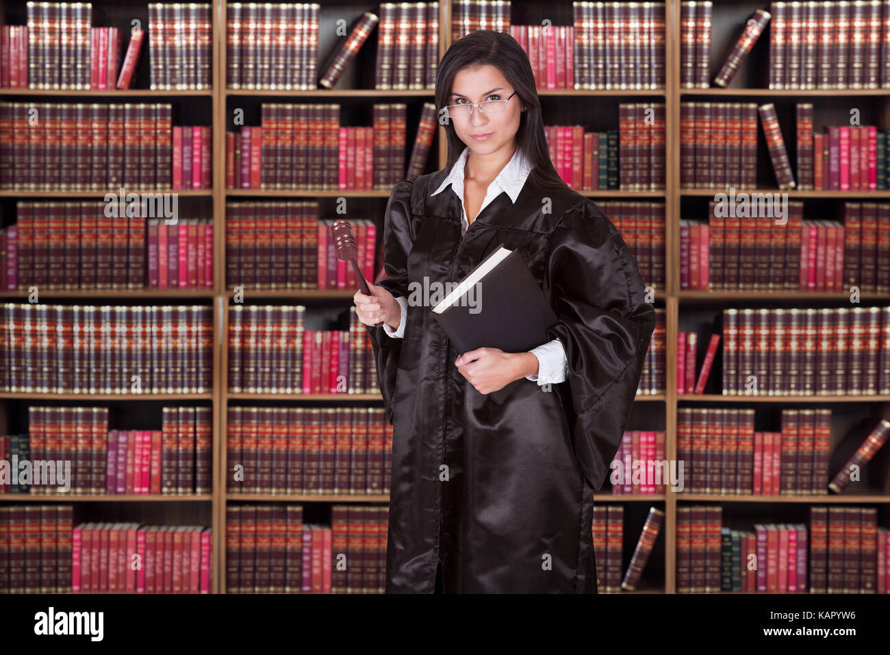Ritratto di grave giudice femmina azienda martello e libro contro i ripiani Foto Stock