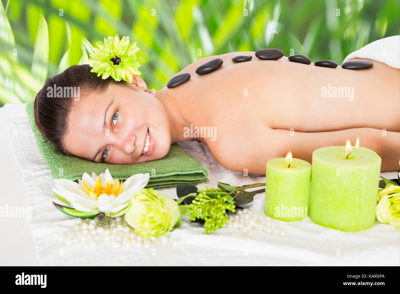 Ritratto di felice giovane donna ricevere hot stone therapy in beauty spa Foto Stock