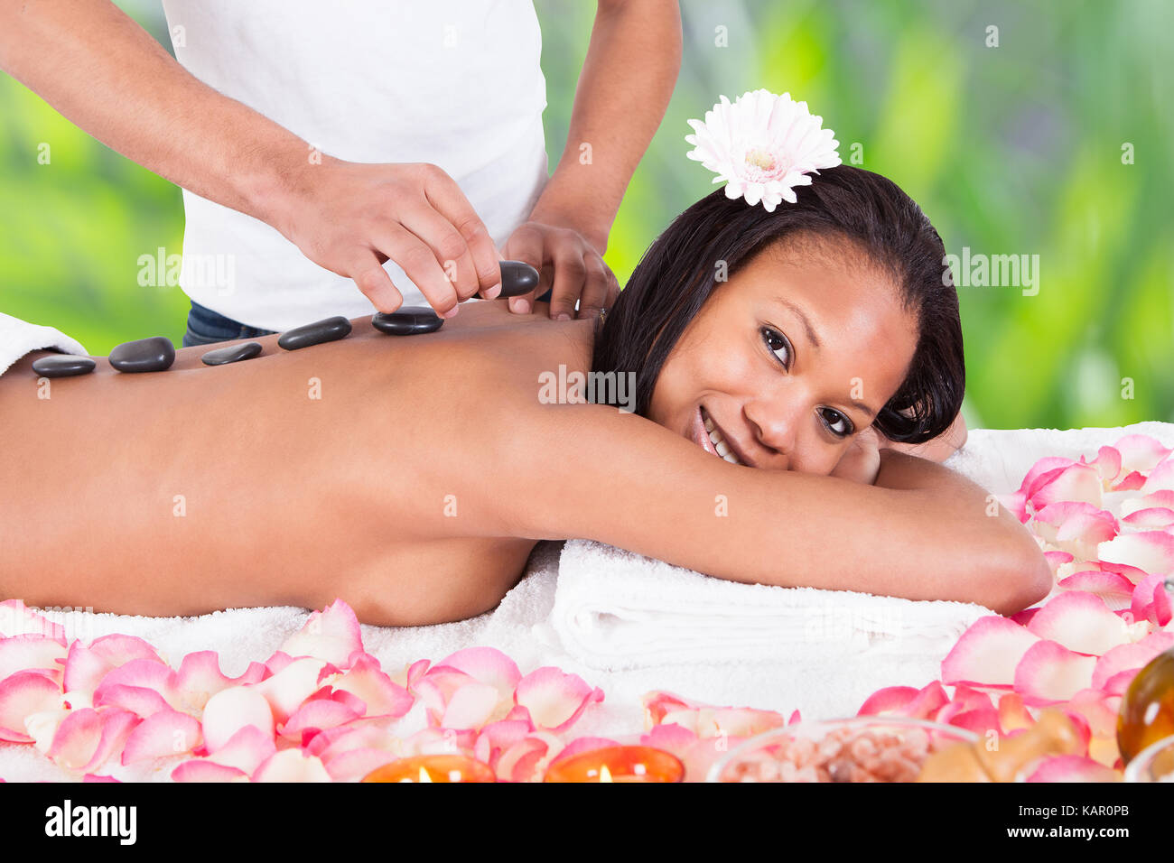 Ritratto di sorridente giovane donna getting hot stone therapy a spa salone Foto Stock