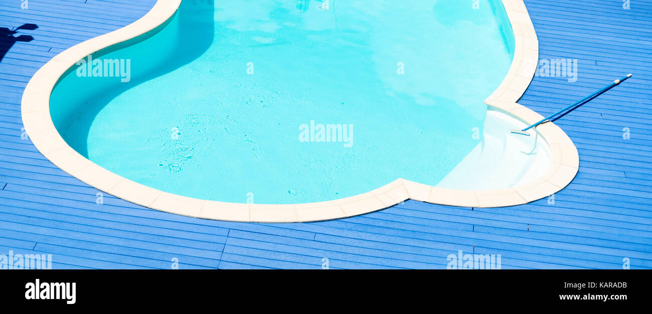 Primo piano di una piscina circolare con acqua chiara, blu brillante ponte di legno e una scopa di pulizia Foto Stock