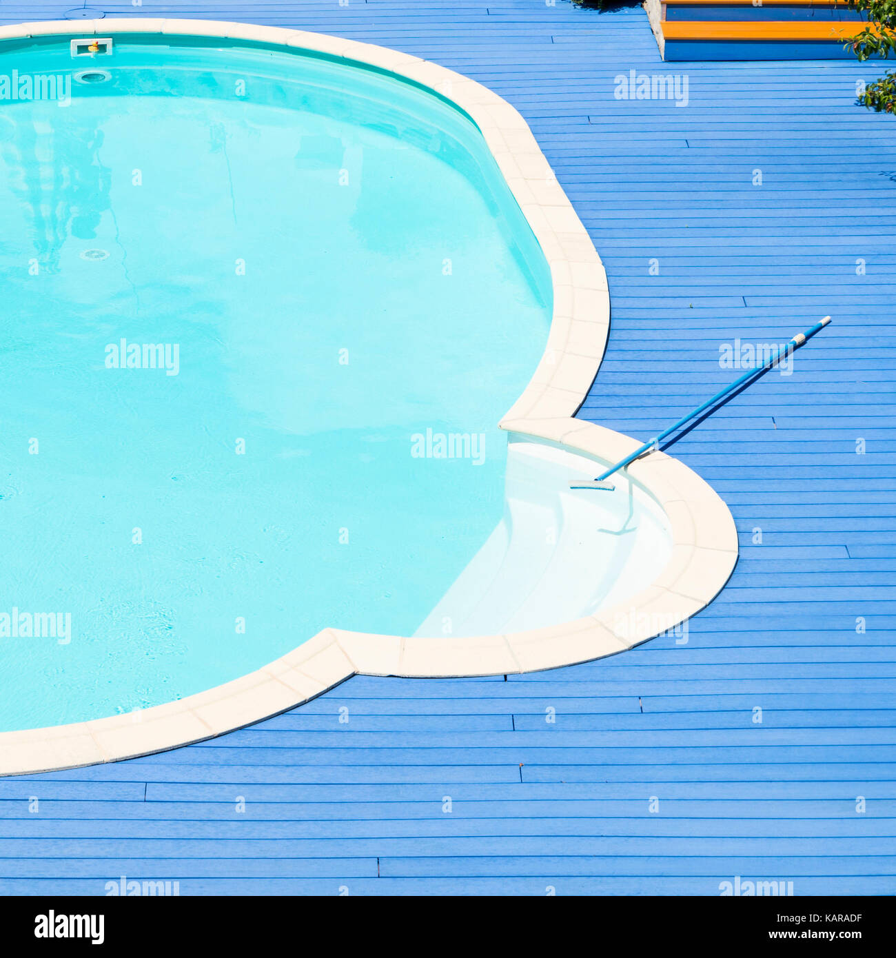 Primo piano di una piscina circolare con acqua chiara, blu brillante ponte di legno e una scopa di pulizia Foto Stock