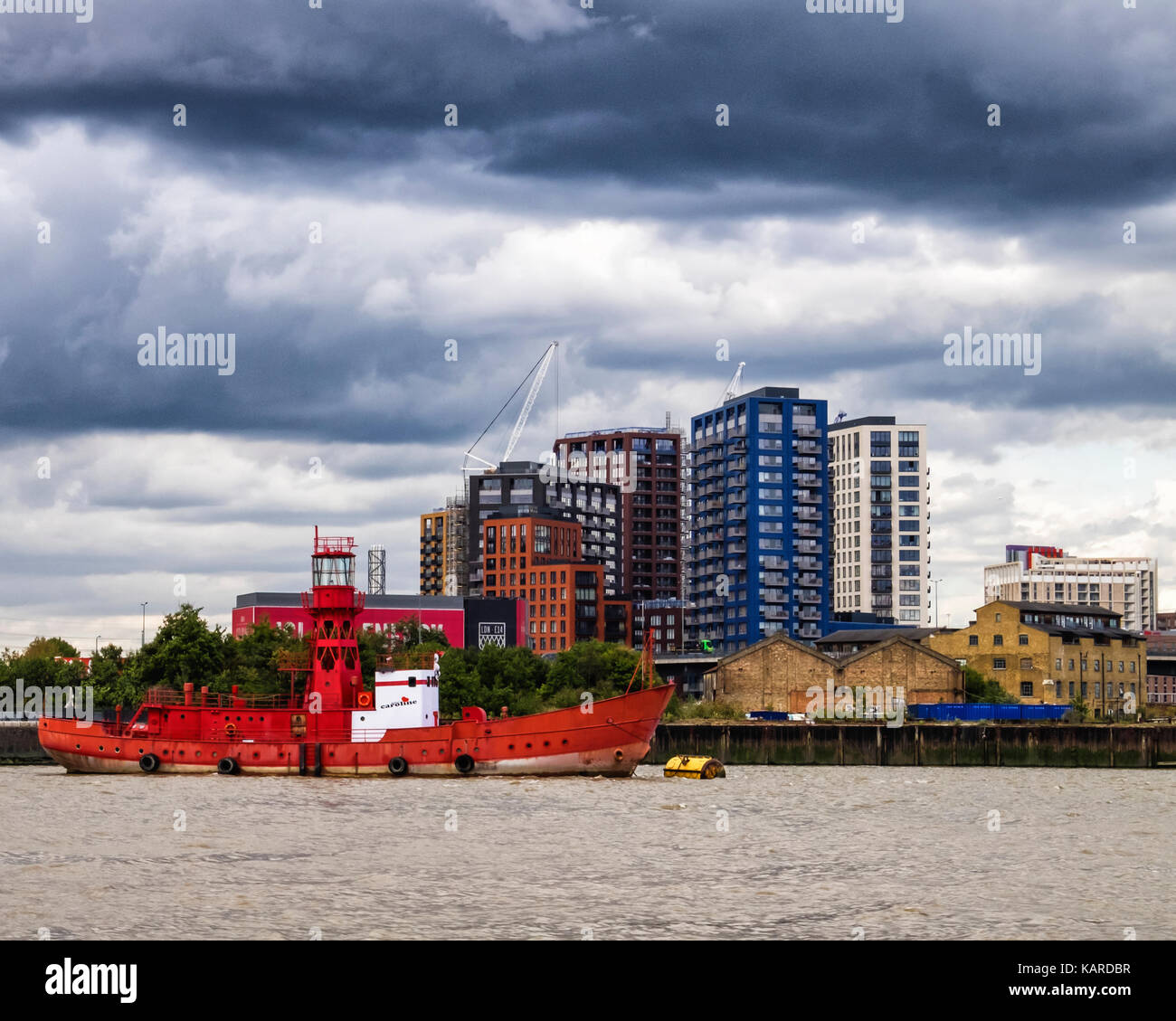 Londra,faro rosso barca,Caroline sul fiume Tamigi e London City isola,nuovo edificio sede di sviluppo da parte di Ballymore Gruppo.Black Storm nuvole. Foto Stock