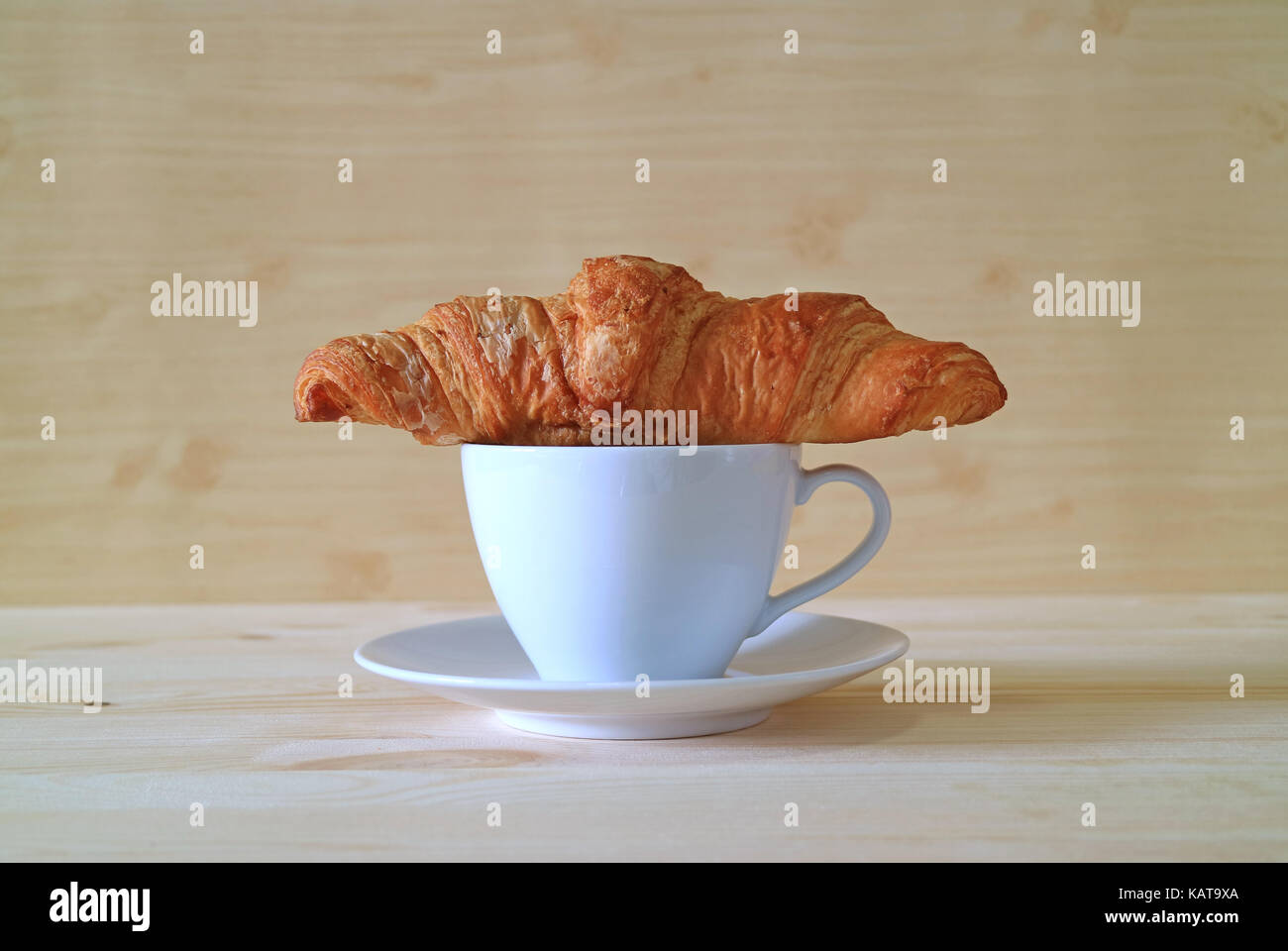 Vista frontale del croissant al burro con una tazza di caffè sul tavolo in legno Foto Stock