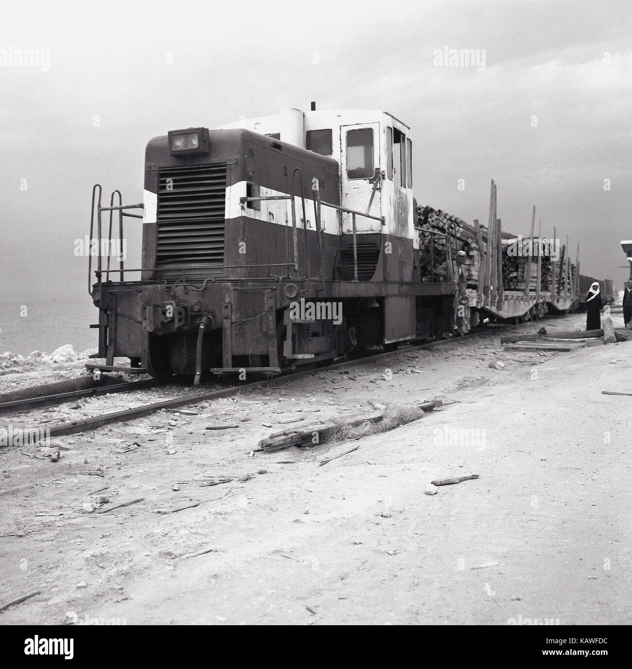 Degli anni Cinquanta, storica foto scattata in Arabia Saudita da J Tutti i contanti di una grande locomotiva caricato di trazione treno merci carri attraverso il deserto in questo momento di esplorazione petrolifera del paese. Foto Stock