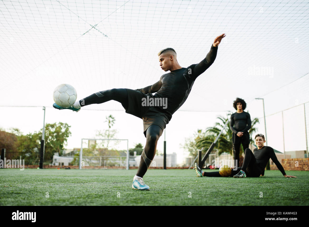 Giocatore di calcio calciare la palla. Giovani calciatori la pratica sul campo di calcio. Foto Stock