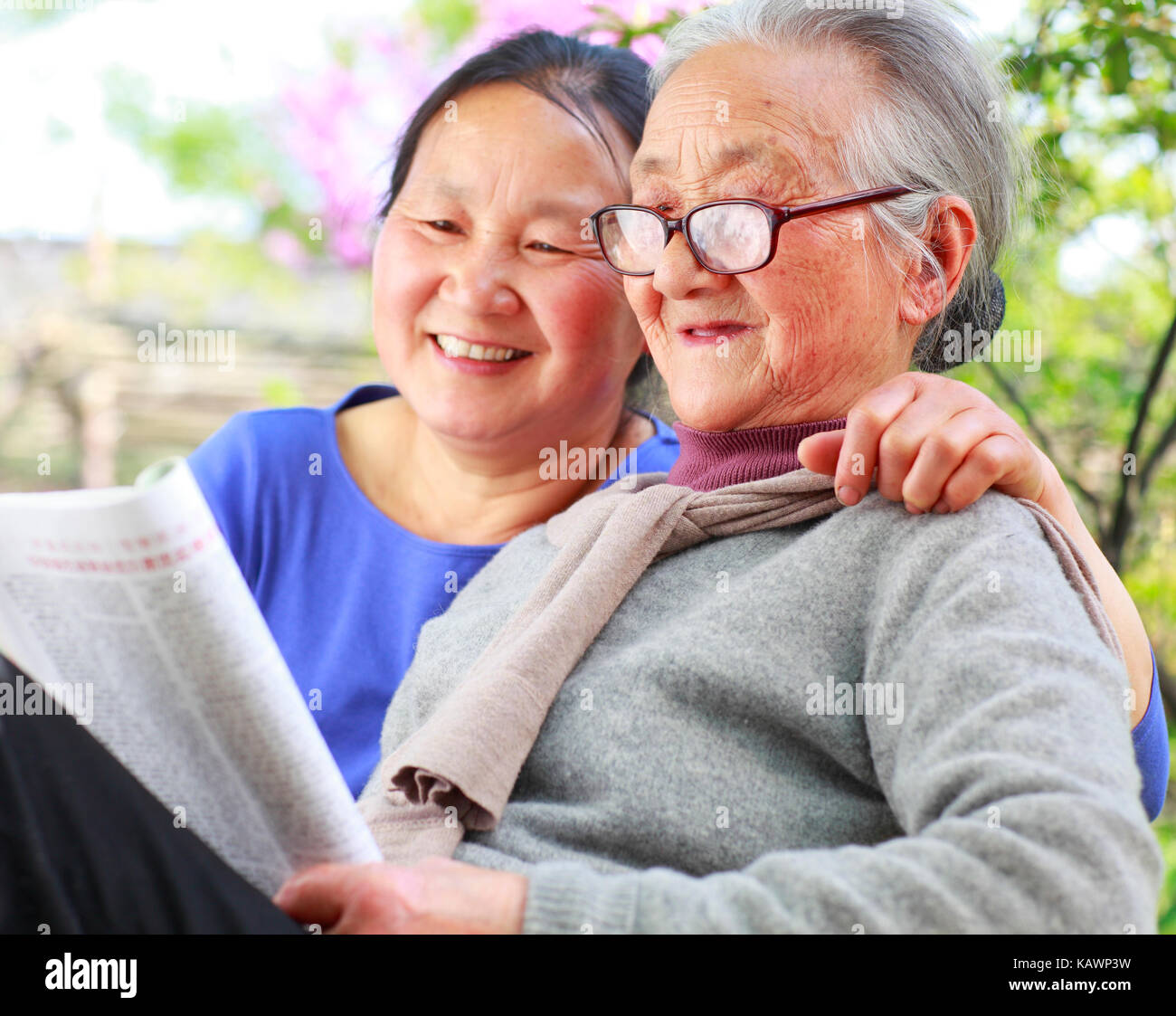 90 anni senior donna asiatica la lettura di libro in cantiere con sua figlia adulta insieme Foto Stock