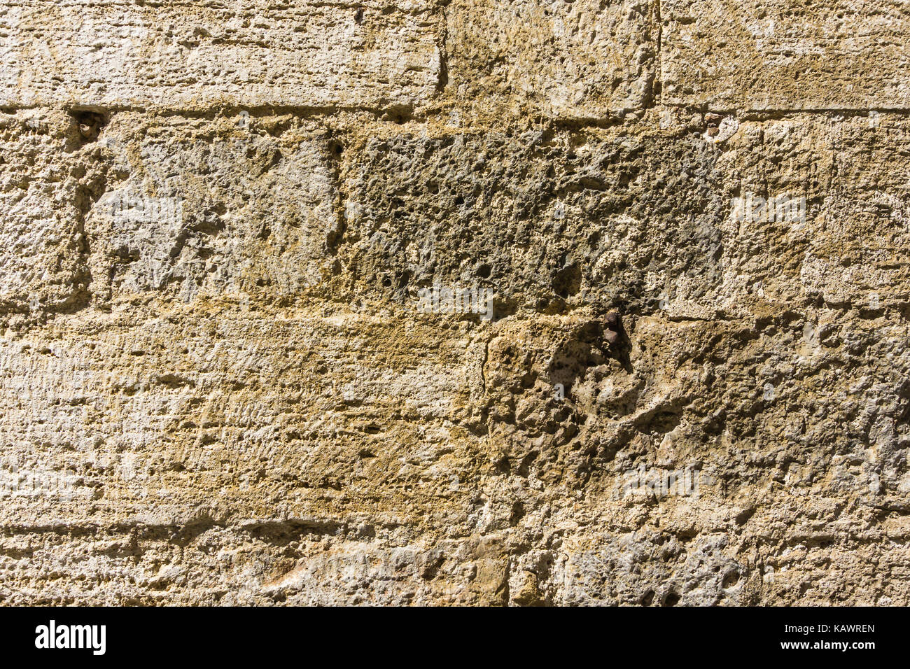 Foto orizzontale con la texture della parete tipici in toscana italia. La pietra utilizzata è di origine vulcanica tuf giallo con fori e boschetti. Foto Stock