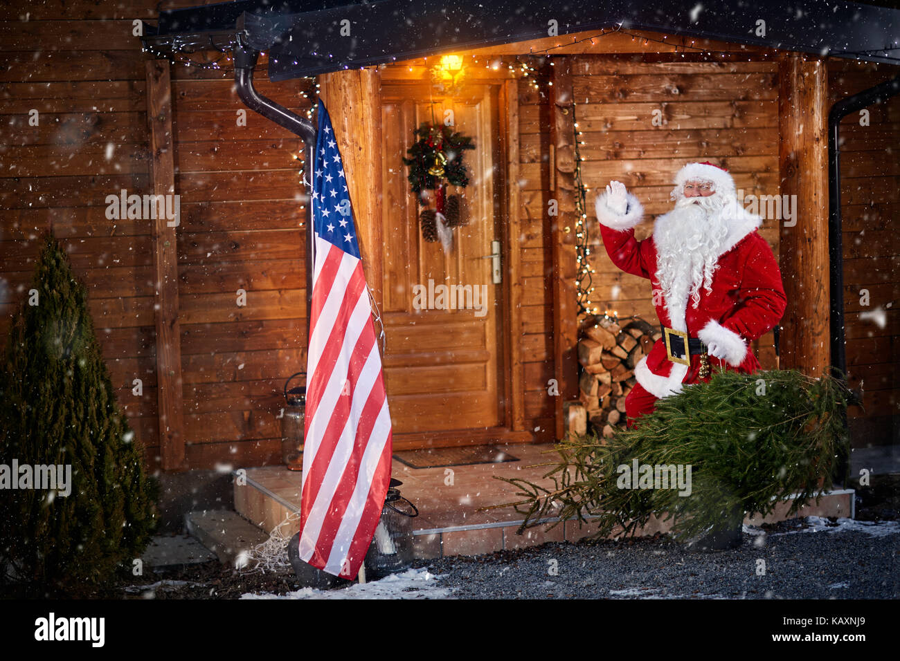 Babbo Natale in piedi all'aperto sotto la neve e la tenuta albero di natale Foto Stock