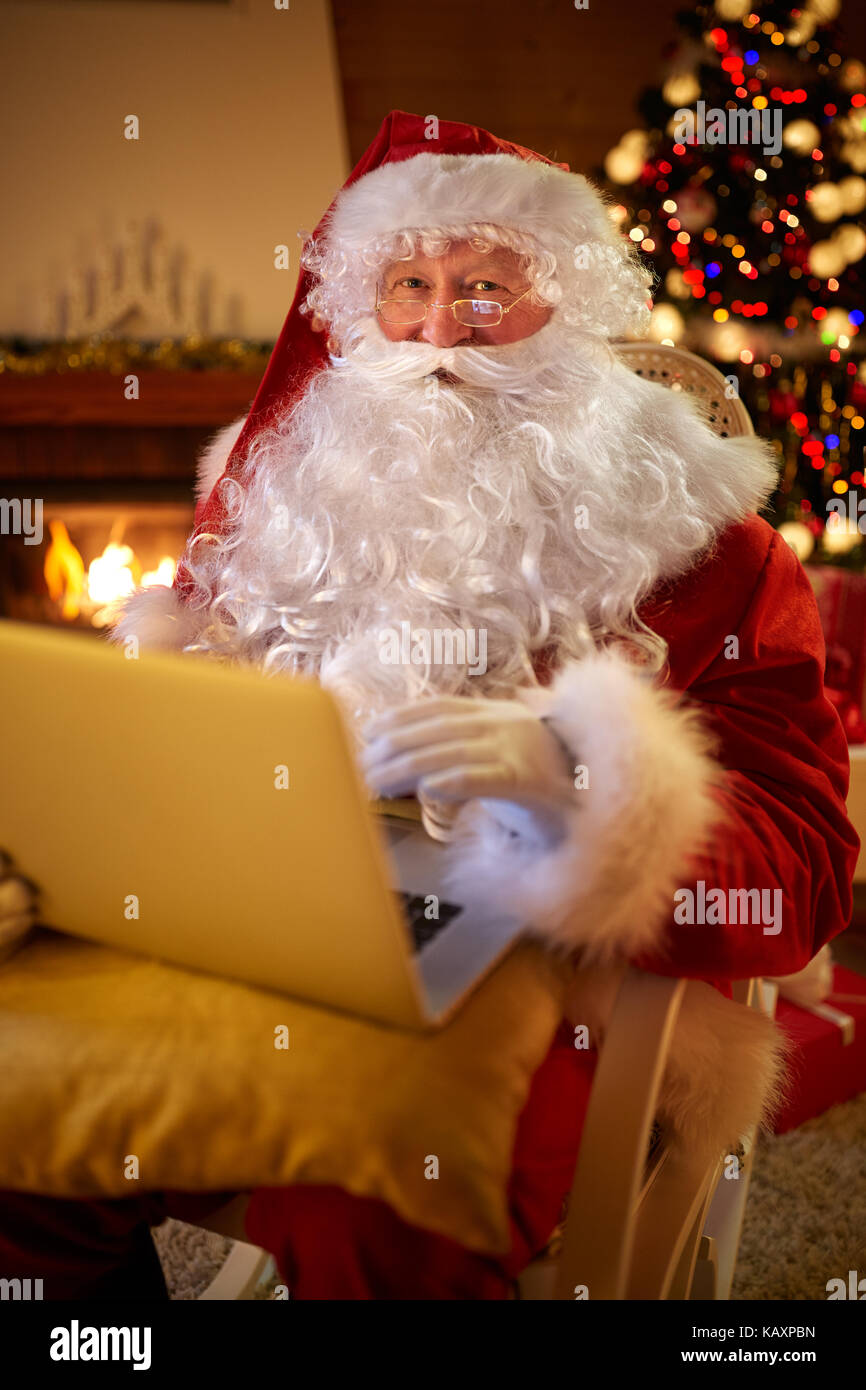 Babbo Natale la lettura di messaggi di posta elettronica sul computer portatile desidera richiedente presente elenco bambini Foto Stock